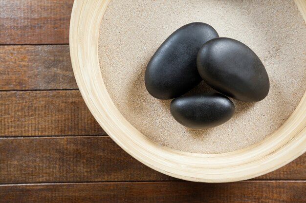 Tres cantos rodados de piedra en un cuenco de madera