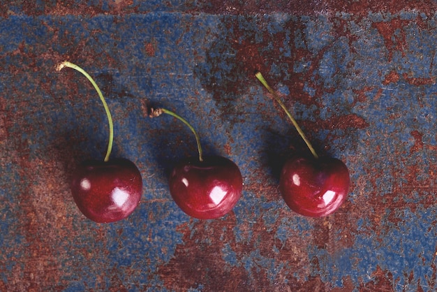Tres cerezas maduras en la mesa vieja