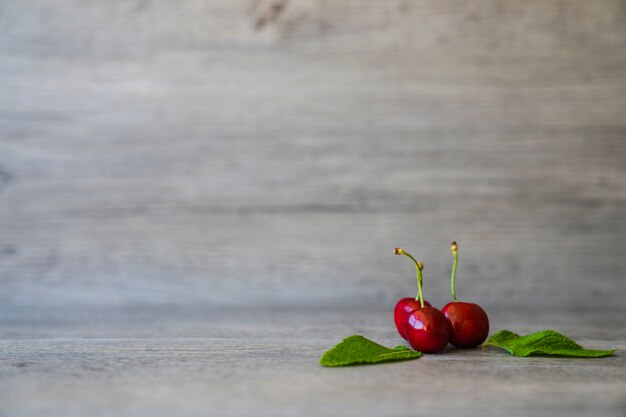 Tres cerezas sabrosas con fondo de madera