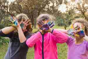 Foto gratuita tres chicas cubriendo sus caras con palmas pintadas