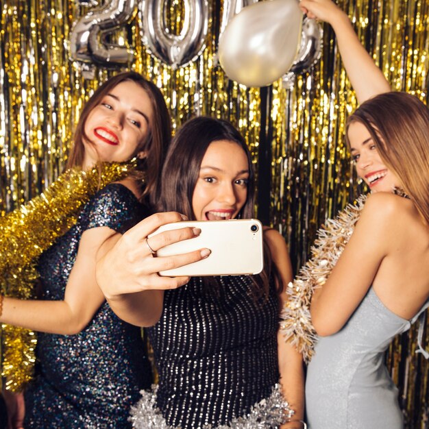 Tres chicas felices haciendo un selfie en celebración de año nuevo