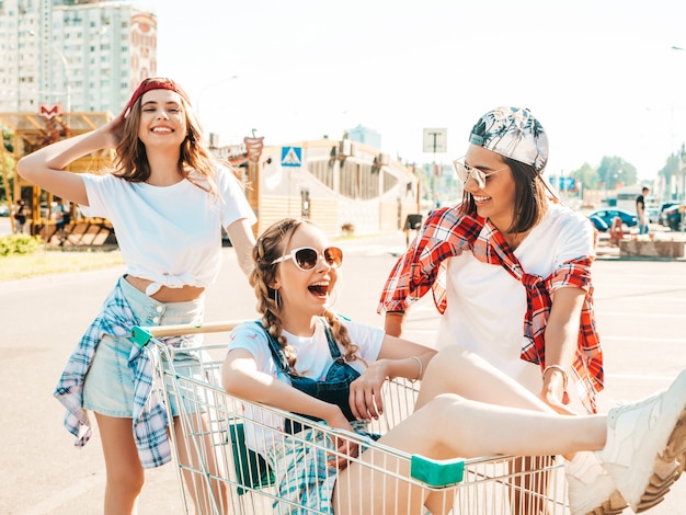 Tres chicas guapas jóvenes divirtiéndose en el carrito de compras