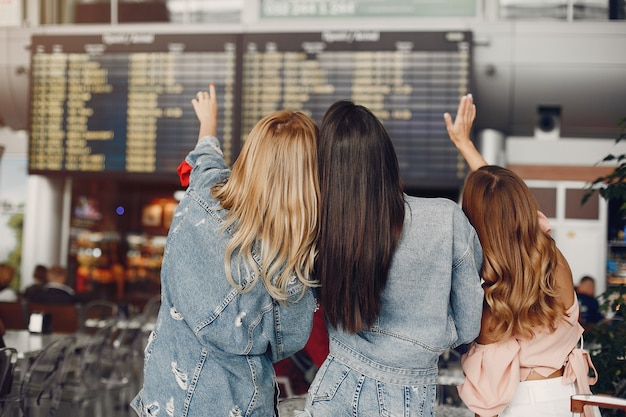 Tres chicas guapas de pie junto al aeropuerto