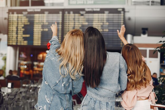 Tres chicas guapas de pie junto al aeropuerto
