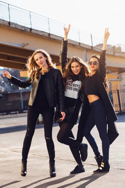 Tres chicas guapas que se divierten al aire libre. Estado de ánimo urbano de estilo de vida. Fondo de la ciudad de noche. Mejores amigos con traje casual negro.