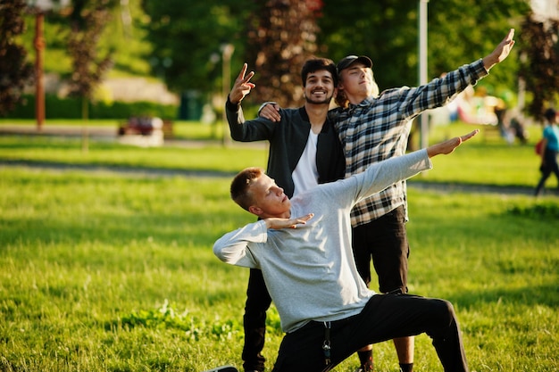 Foto gratuita tres chicos multiétnicos plantean al aire libre