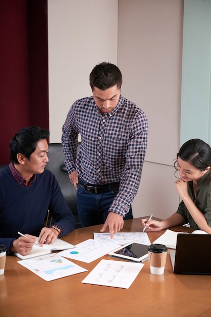 Tres colegas discutiendo el informe comercial examinando datos estadísticos