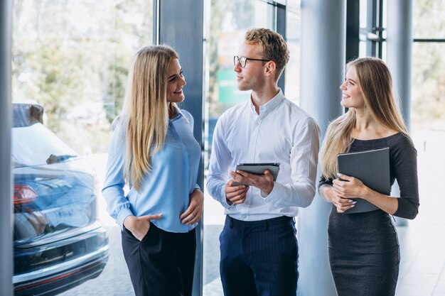 Tres colegas que trabajan en una sala de exposición de automóviles