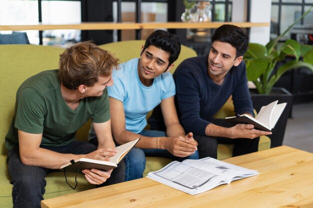 Tres compañeros hablando y estudiando juntos