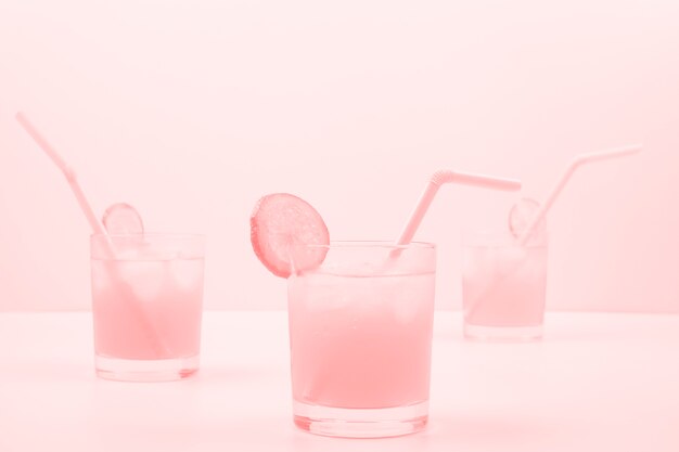 Tres copas de cóctel rosa sobre fondo de color