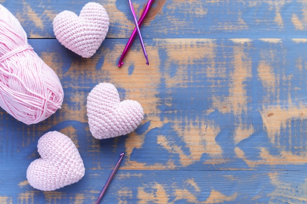 Tres corazones rosas tejidos a mano con ovillo de lana. Vista superior