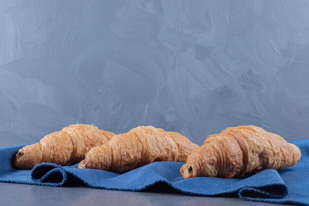 Tres croissant francés fresco en una servilleta azul.