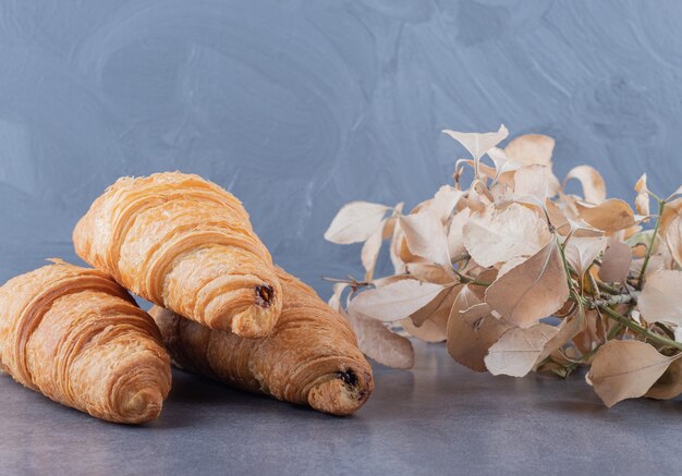 Tres croissant francés fresco sobre fondo gris.