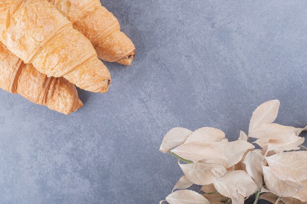 Tres croissant francés fresco sobre fondo gris.