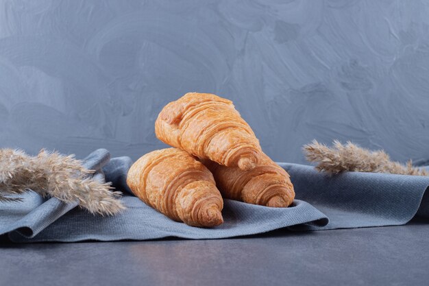 Tres croissants franceses frescos en servilleta de algodón gris.