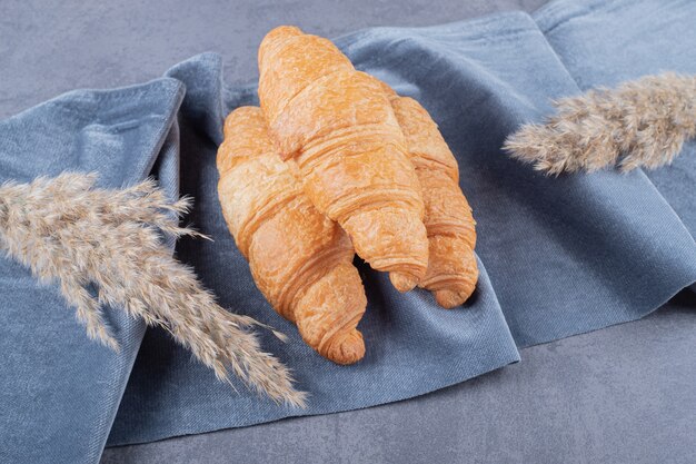 Tres croissants recién horneados sobre fondo gris.