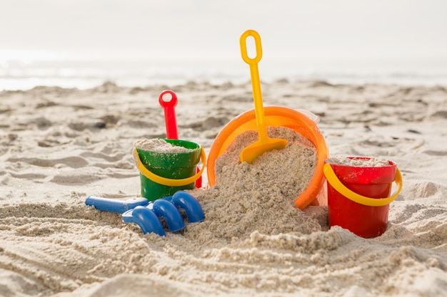 Foto gratuita tres cubos de arena y una pala en la playa