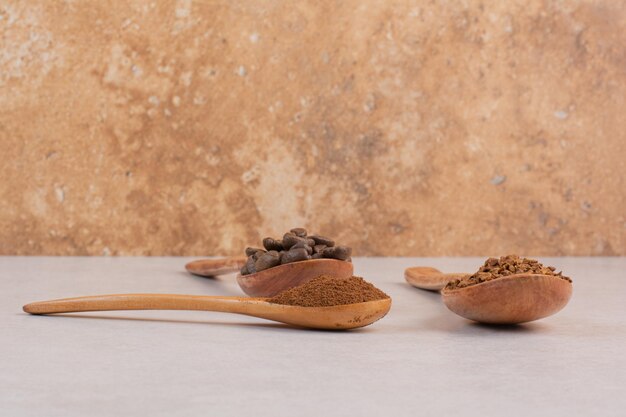 Tres cucharas de madera llenas de granos de café y cacao en polvo. Foto de alta calidad
