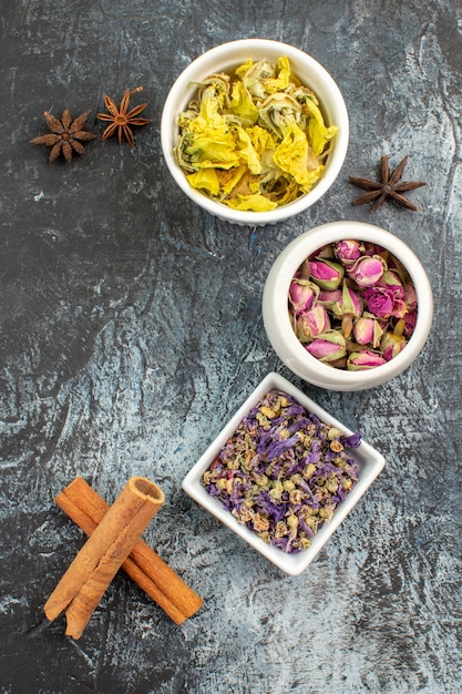 Tres cuencos de flor seca y ramitas de canela y anís en gris