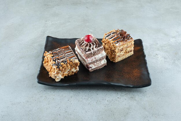 Tres deliciosos pasteles en placa negra. Foto de alta calidad