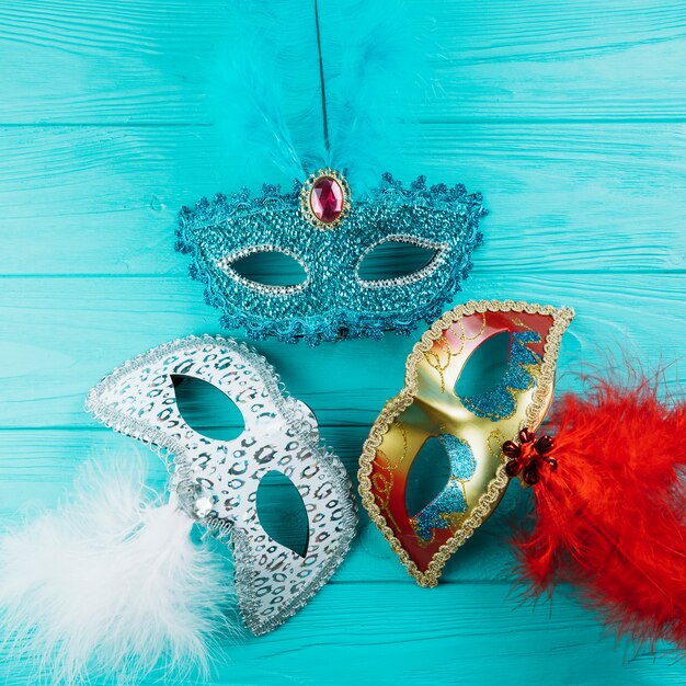 Tres diferentes tipos de mascarada máscara de carnaval con plumas en mesa de madera