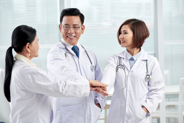 Tres doctores dando gesto de unidad que simboliza el trabajo en equipo