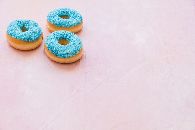 Tres donuts azules sobre fondo rosa