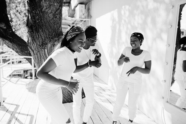 Tres elegantes amigos afroamericanos visten ropa blanca Moda callejera de jóvenes negros Hombre negro con dos chicas africanas bailando estilo gangsta rap