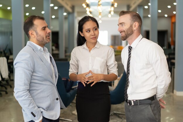 Tres empresarios positivos charlando en la oficina