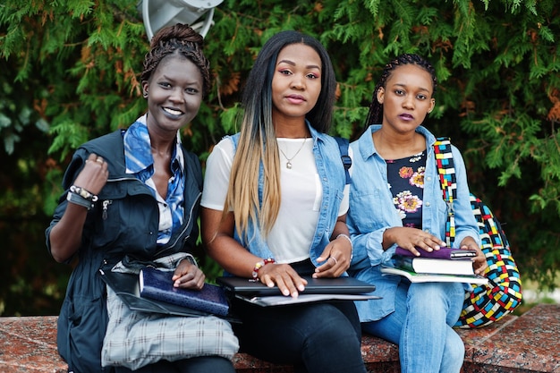 Tres estudiantes africanas posaron con mochilas y artículos escolares en el patio de la universidad
