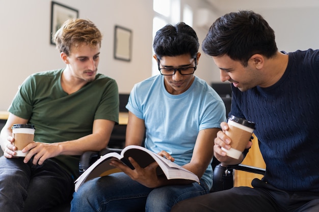 Tres estudiantes enfocados que estudian juntos y beben