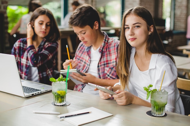 Foto gratuita tres estudiantes con gadgets en el café