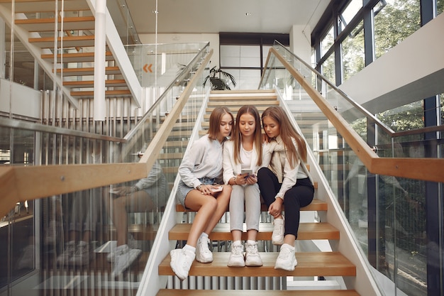 Tres estudiantes sentados en una escalera con un teléfono