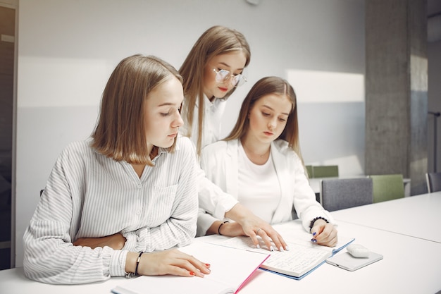 Tres estudiantes sentados a la mesa en una clase.