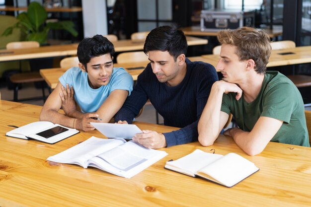 Tres estudiantes serios que estudian y usan la tableta