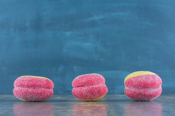 Foto gratuito tres galletas en forma de melocotón, sobre la superficie de mármol.