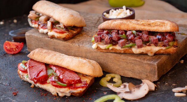 Tres grandes porciones de bocadillos baguette con alimentos mixtos.