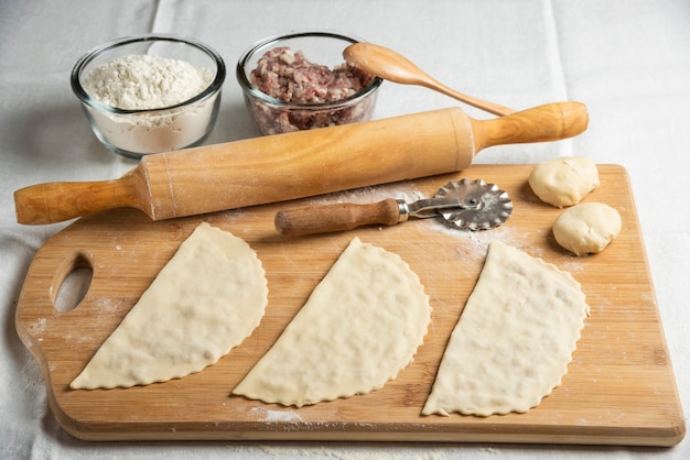 Tres gutabs de carne cruda sobre tabla de madera. Cocina nacional azerbaiyana.