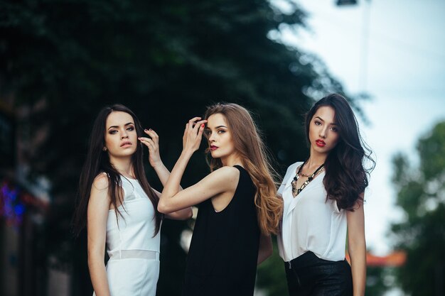 Tres hermosas chicas posando en una calle de la ciudad por la noche