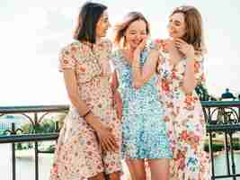 Foto gratuita tres hermosas chicas sonrientes en vestido de verano de moda posando en la calle