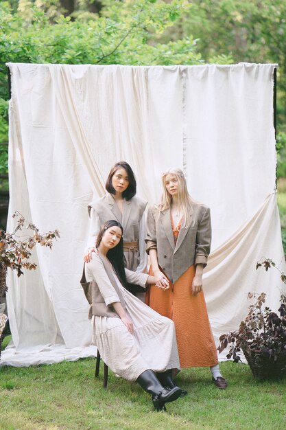 Tres hermosas mujeres de pie, sentado y mirando en el jardín.