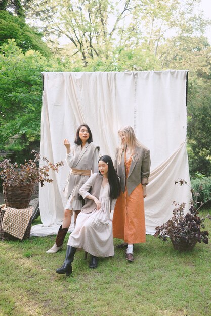 Tres hermosas mujeres de pie, sentado y mirando en el jardín.