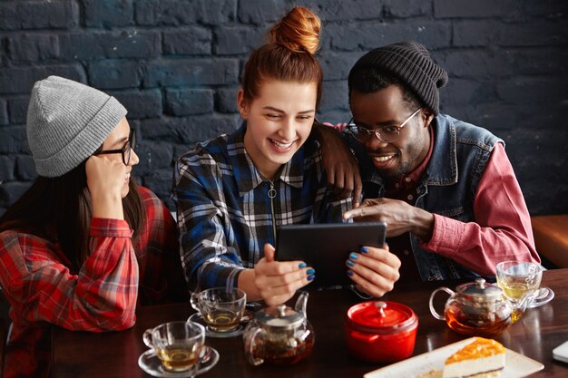 Tres hipsters divirtiéndose en la cafetería.