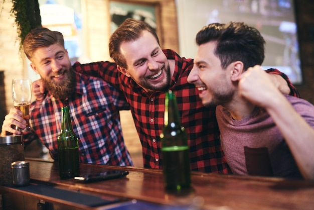 Tres hombres disfrutando juntos en el pub