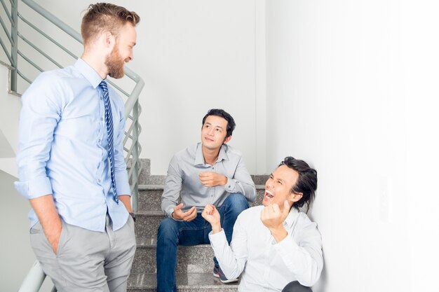 Tres hombres de negocios sonrientes charlando en las escaleras