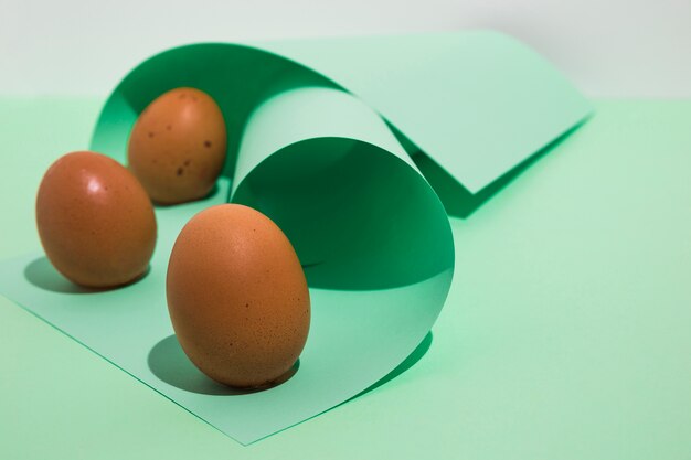 Tres huevos de gallina marrón con papel enrollado en mesa