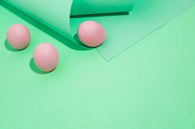 Tres huevos de pascua rosa con papel enrollado.