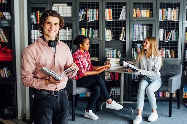 Tres jóvenes adolescentes hablando de proyecto, trabajando juntos en la sala de la biblioteca de reuniones