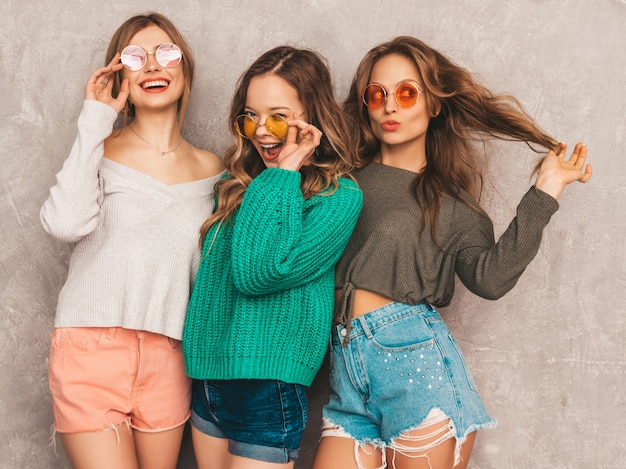 Tres jóvenes hermosas sonrientes hermosas chicas en ropa de moda de verano. Sexy mujer despreocupada posando. Modelos positivos divirtiéndose en gafas de sol redondas