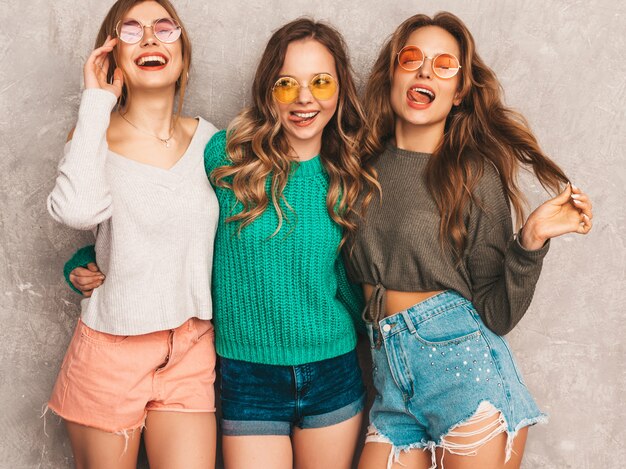 Tres jóvenes hermosas sonrientes hermosas chicas en ropa de moda de verano. Sexy mujer despreocupada posando. Modelos positivos divirtiéndose en gafas de sol redondas